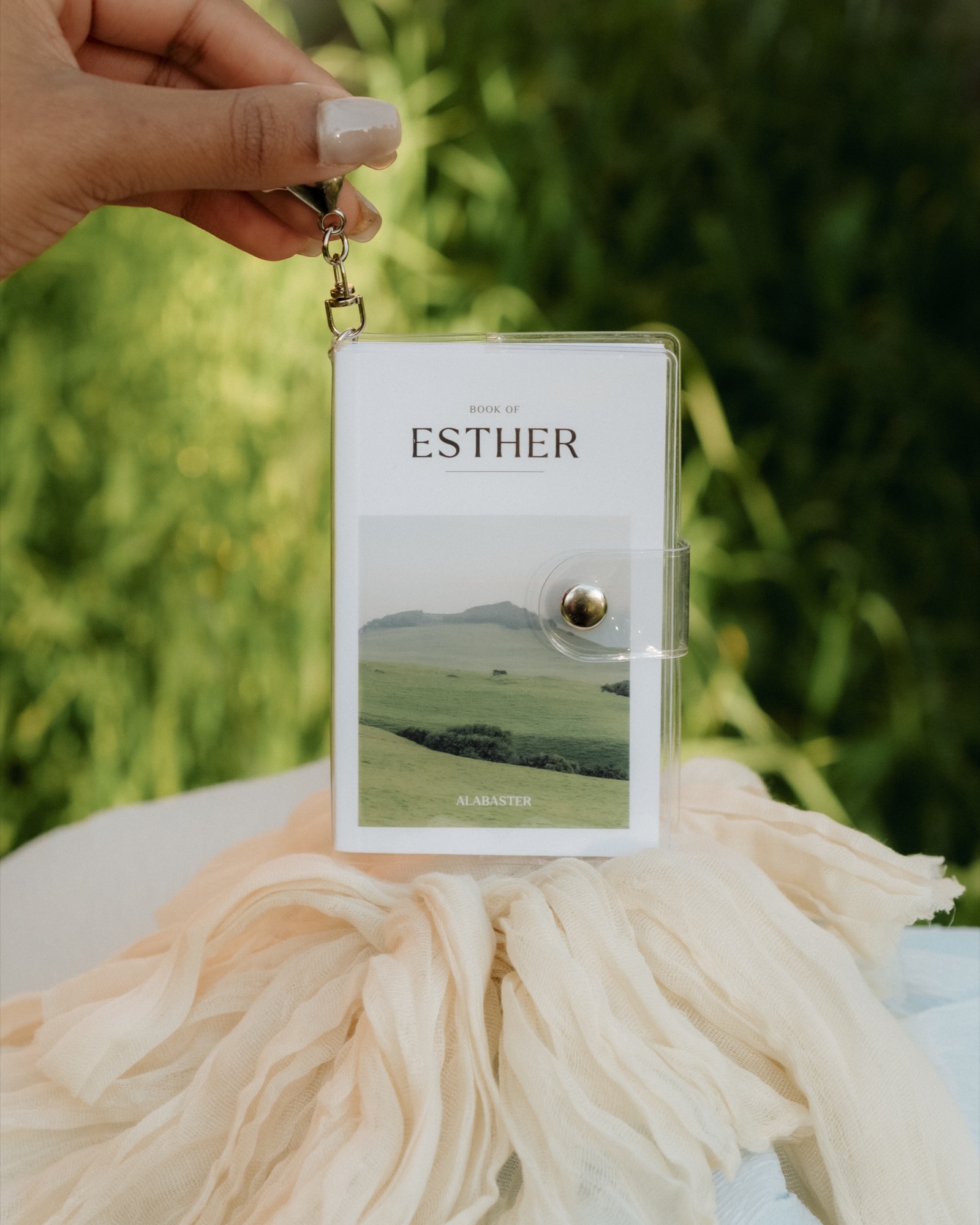 Mini Bibles: Book of Esther in its clear snap pouch with keychain, held in hand, Mother's Day 2026 shoot