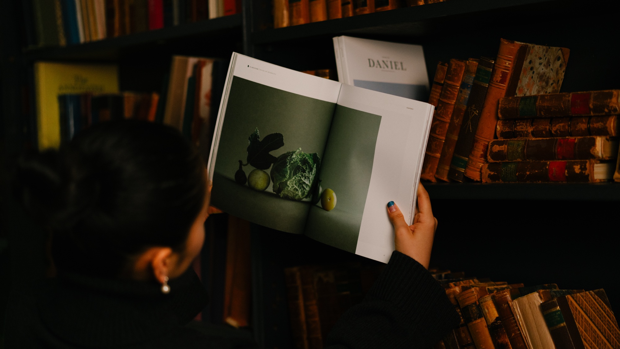 Alabaster Rebrand: Interior spread in hand, still-life chapter opener, Book of Hebrews; Daniel softcover behind. New York rebrand shoot 2025